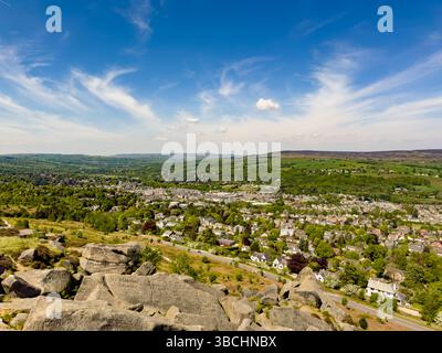 Vue sur Ilkley depuis les rochers de vache et de veau, avec graffiti sculptés historiques visibles sur les rochers du premier plan. West Yorkshire. ROYAUME-UNI Banque D'Images