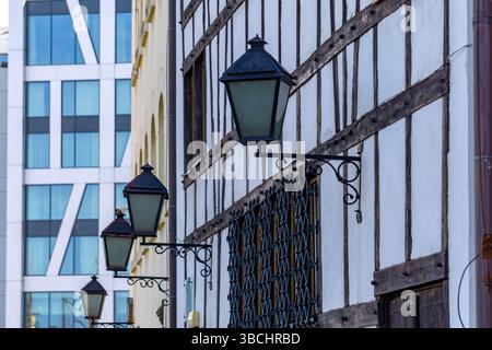 fragment d'une façade de bâtiment à colombages avec des poutres en bois caractéristiques. Des lanternes décoratives en fer forgé sont montées sur le mur. Dans le backgro Banque D'Images
