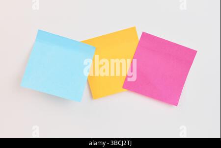 Trois notes adhésives en bleu, jaune et rose sont affichées de manière créative Banque D'Images