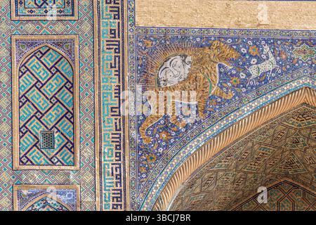 Des carreaux de mosaïque colorés avec un motif tigre et soleil embellissent la façade de Sherdor Madrasa sur la place Registan, Samarcande, Ouzbékistan. Banque D'Images