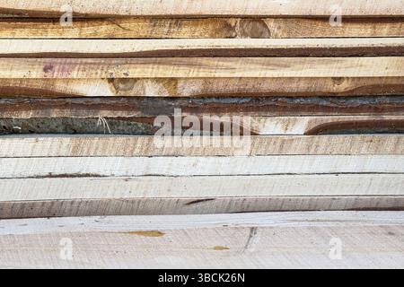 Gros plan de planches de bois scié brut avec une texture d'écorce et de grain de bois. Aucune personne, adapté aux arrière-plans, à la menuiserie ou à un usage éditorial. Banque D'Images