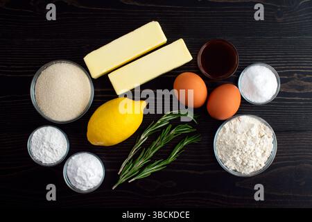 Biscuits au sucre romarin-citron ingrédients : farine, beurre, sucre, œufs et autres ingrédients de biscuits sur une table en bois foncé Banque D'Images