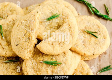 Biscuits au sucre au romarin et au citron empilés sur du papier d'emballage brun : vue en gros plan des biscuits au sucre et des feuilles de romarin éparpillées sur du papier brun Banque D'Images