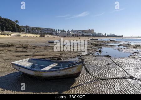 Cadix, Espagne - 16 janvier 2021 : vue sur la plage de la Caleta à Cadix avec des bateaux de pêche en bois bloqués à marée basse Banque D'Images