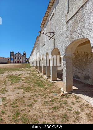 Ancien sanctuaire religieux au cap Espichel à Sesimbra Portugal avec de longues arcades symétriques et une façade historique de l'église sous un bleu vif Banque D'Images