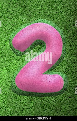 Le numéro deux dans une texture éponge rose, surélevé en 3D à partir du fond vert Banque D'Images