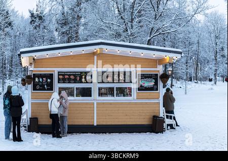 Vyborg, Russie, 6 janvier 2025 : par une journée d'hiver glaciale, les citadins et les touristes grignotent et se réchauffent avec des boissons chaudes dans un étal du parc Monrepo Banque D'Images