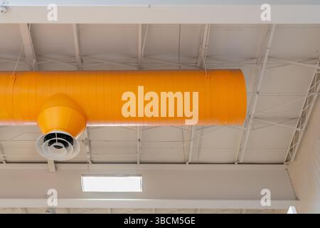 Bâtiment intérieur HVAC, systèmes mécaniques, conduit orange, tuyaux de ventilation, avec diffuseur blanc, suspendu au plafond d'un grand espace ouvert. Banque D'Images