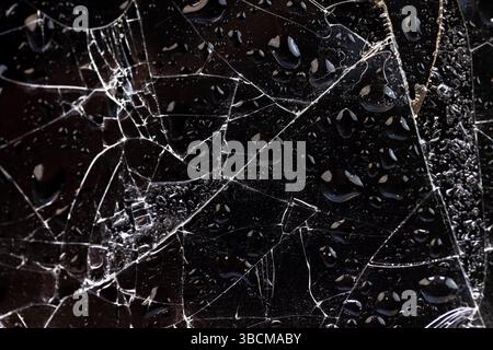 gouttelettes d'eau recouvertes de verre brisé avec beaucoup de dommages et de morceaux sur un fond noir, verre mince humide cassé en de nombreux morceaux Banque D'Images