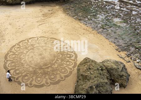 France - 21 octobre 2020 : un artiste de rue talentueux dessine des mandala dans le sable sur la plage de Biarritz Banque D'Images