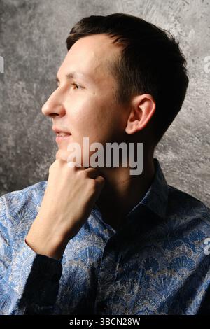 Un jeune homme réfléchi dans une pose artistique sur un fond subtil et apaisant Banque D'Images