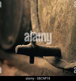 À l'intérieur d'une ancienne cave vinicole en France, un tonneau de vin usé se tient en évidence. La poussière recouvre le bois, soulignant le processus de vieillissement du vin fin. Banque D'Images