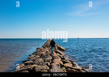 La femme marche sur la taupe de la rivière Pärnu en été. Jetée en pierre populaire dans la ville de Pärnu en Estonie. Banque D'Images