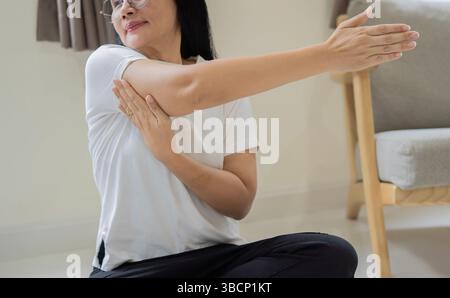 Femme mature pratiquant un exercice de relaxation à la maison. Femme âgée heureuse ayant une séance de yoga. Mise au point sélective. Banque D'Images