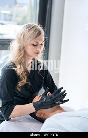 Cosmétologue réalisant une thérapie de drainage lymphatique chez l'homme Banque D'Images