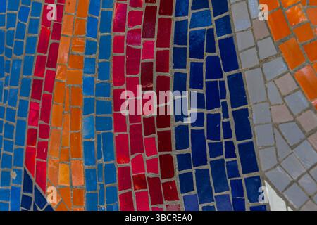 Vue rapprochée de carreaux de mosaïque vibrants en rouge, orange, bleu et gris disposés dans des motifs fluides, parfait pour les projets artistiques et de design. Banque D'Images