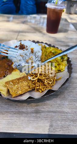 gros plan de riz pecel avec nouilles frites, tempeh, tofu et omelette sur la plage Banque D'Images