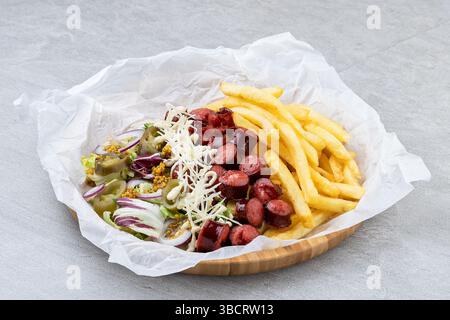 Saucisse fumée avec salade jalapeno frites et parmesan servie dans un plateau en bambou recouvert de papier. Banque D'Images