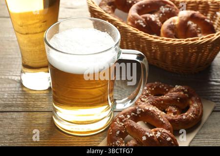 Délicieux bretzels et tasses en verre de bière sur la table en bois, gros plan Banque D'Images