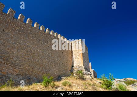 Vue détaillée du mur crénelé de la forteresse médiévale s'élevant contre un ciel bleu profond dans la ville historique d'Albarracin. Banque D'Images