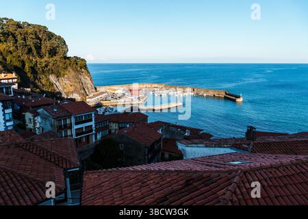 Pittoresque ville côtière nichée sur une colline surplombant un port calme rempli de bateaux, la scène baignée de soleil. Lastres, Asturies Banque D'Images