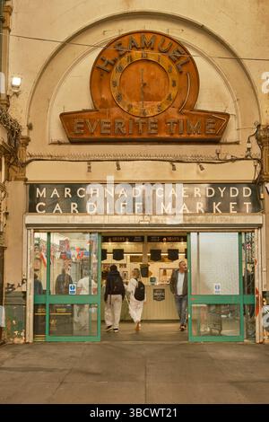 Entrée au marché de Cardiff (Marchnad Caerdydd) avec horloge H. Samuel Everite vintage au-dessus de la porte. Les gens entrent dans le marché intérieur historique. Banque D'Images