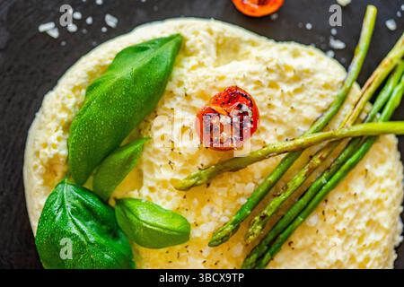 Omelette avec asperges sautées, tomates et basilic sur une assiette noire. Gros plan. Vue de dessus. Photo de haute qualité Banque D'Images