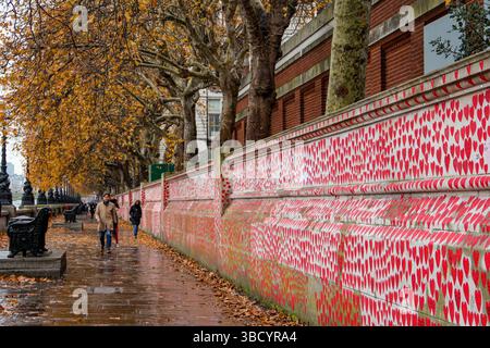 Albert Embankment, des gens marchant le long du National COVID Memorial Wall sur la rive sud de Londres, bordés de cœurs rouges, de feuilles d’automne tombant sur un rai Banque D'Images