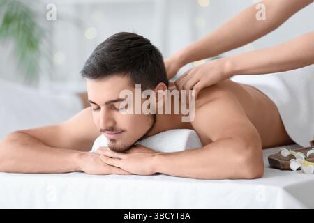 Jeune homme se faisant masser dans le salon de spa Banque D'Images