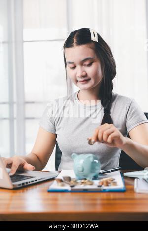 Femme d'affaires économisant de l'argent avec tirelire et pièces de monnaie sur le bureau, la planification financière et le concept d'investissement. Jeune femme asiatique faisant pile de pièces. inves Banque D'Images