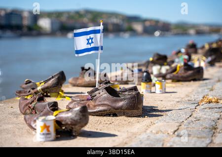 Budapest, Hongrie - 27 avril 2025 : le drapeau israélien flotte au milieu des « Chaussures sur la rive du Danube » – Un dialogue puissant entre mémoire et solidarité Banque D'Images