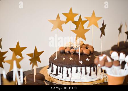table sucrée pour la fête d'anniversaire des enfants avec gâteau décoré d'étoiles comme pièce maîtresse. Beau gâteau fondant avec des étoiles dorées comme décoration principale de fest Banque D'Images