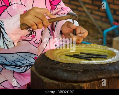 Femme embossant une plaque de bronze au village Silver smith-3, région de Phnom Penh, Cambodge Banque D'Images