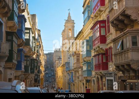 Valletta Street Malta, vue sur une rue pittoresque de la Valette montrant des bâtiments avec balcons fermés typiques du centre historique de la ville, Malte Banque D'Images