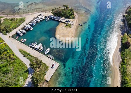 Vue aérienne d'un petit port de plaisance à l'entrée du canal de Nea Potidea à Halkidiki, Grèce, avec des eaux turquoises, des rives sablonneuses et des bateaux ancrés Banque D'Images