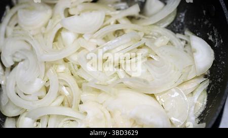 Oignons tranchés frire dans une poêle chaude avec de l'huile. Banque D'Images