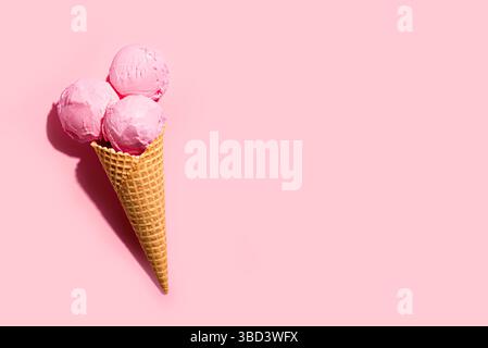 Cuillères à crème glacée rose fraise dans un cône de gaufre sur fond pastel rose, design créatif avec une lumière dure, espace de copie. Crème glacée aux baies d'été à la mode Banque D'Images