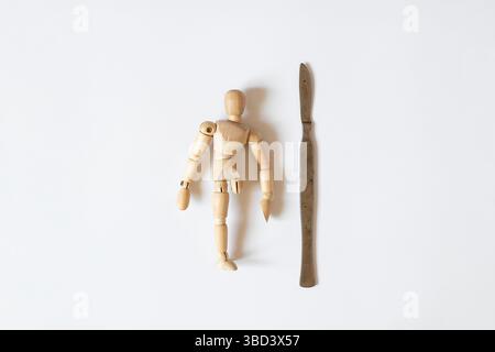 Homme en bois avec jambe amputée et scalpel chirurgical sur fond blanc , traumatisme, prothèses et chirurgie , santé et réadaptation Banque D'Images