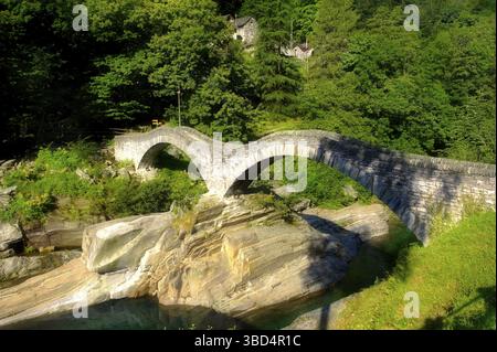 Pont de pierre à travers le ruisseau rocheux des contreforts alpins dans la vallée reculée de Val Verzasca, près de Lavertezzo, Tessin, Suisse, Europe Banque D'Images