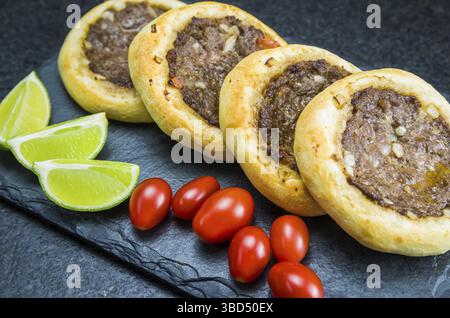 Délicieuse cuisine libanaise (arabe), véritable sfihas sur une assiette en ardoise avec tomates et citrons Banque D'Images