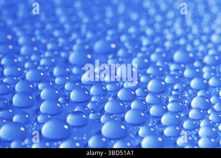 Gros plan, macro de nombreuses gouttes d'eau, gouttelettes, sur une surface bleue, fond Banque D'Images
