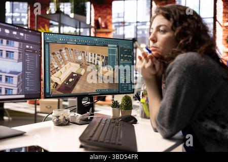 Jeune femme éditrice utilise une interface numérique pour concevoir un plan d'étage d'appartement, travaillant sur un projet de modélisation 3D. Le logiciel architectural permet un rendu professionnel et une configuration de maison virtuelle. Banque D'Images