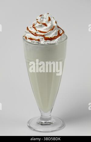 Cocktail d'été milkshake melon et caramel dans un grand verre à facettes sur fond gris Banque D'Images