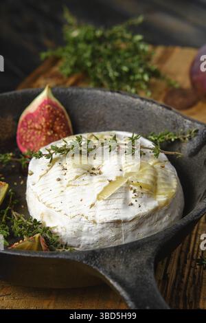 Vue rapprochée du fromage camembert cuit au four et des figues prêtes à cuire sur une poêle Banque D'Images