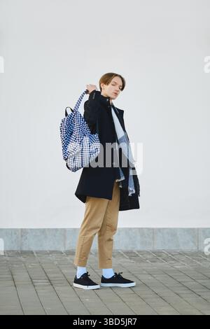 Portrait complet du jeune étudiant avec sac à dos en laine vierge manteau, écharpe et pantalon court extérieur Banque D'Images