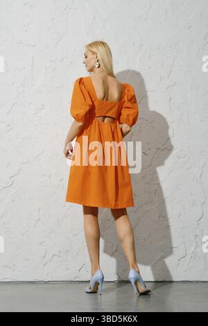 Vue arrière d'une élégante femme adulte vêtue d'une robe ample orange Banque D'Images