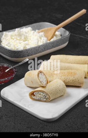 Crêpes maison farcies au fromage cottage sur une assiette de service en marbre Banque D'Images