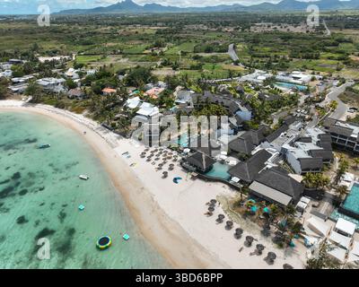 Vue aérienne du complexe en bord de mer avec rangées soignées de parasols, piscine turquoise et cadre côtier Banque D'Images