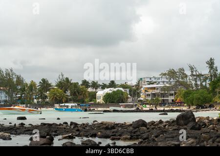 Le Morne, Maurice - 12 mai 2024 : vue rapprochée sur les bâtiments et les palmiers le long de la plage avec des bateaux ancrés dans des eaux peu profondes Banque D'Images