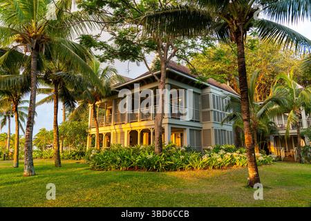 Le Morne, Maurice - 12 mai 2024 : charmant complexe de deux étages avec volets à persiennes et palmiers illuminés par la lumière chaude du coucher de soleil Banque D'Images